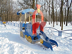 Red children's slide as a locomotive in the snow park area of Ã¢â¬â¹Ã¢â¬â¹the city